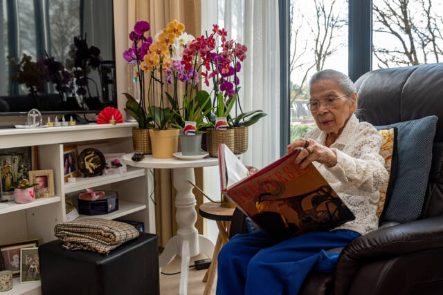 Een bewoonster van de Indische woning leest een boek over Indonesië.