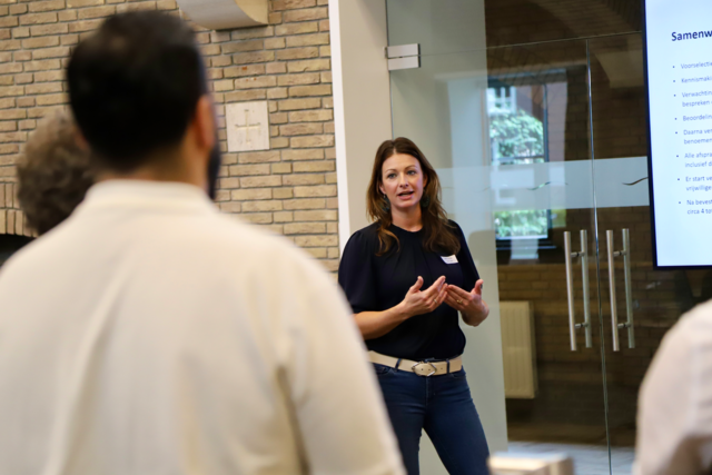 Debby, coördinator vrijwilligerswerk, aan het presenteren tijdens de bijeenkomst