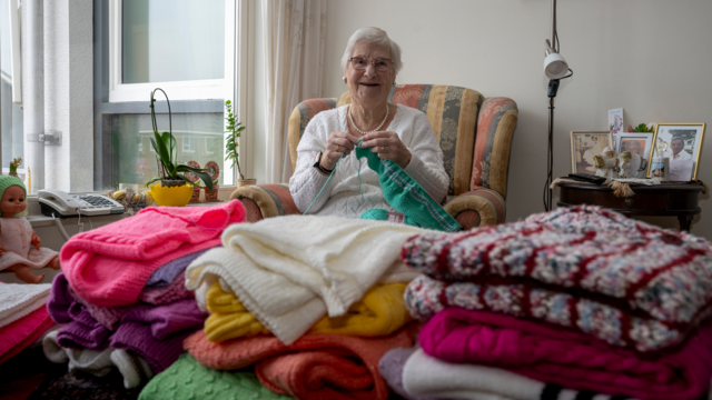 Mevrouw Bergmans bij haar verzameling zelfgebreide truien