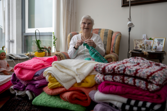 Mevrouw Bergmans bij haar verzameling zelfgebreide truien