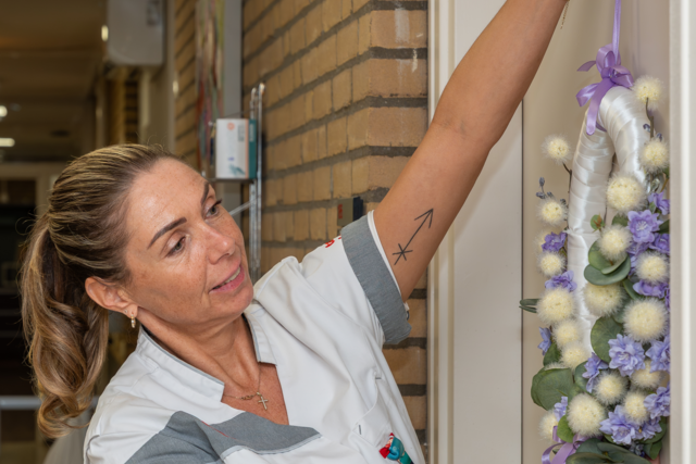 Lissy hangt een krans op bij de deur van een appartement