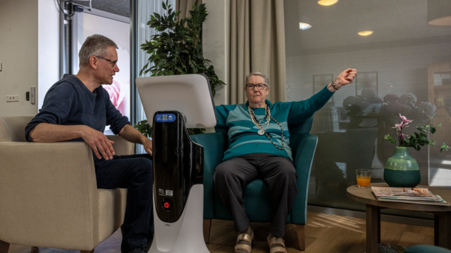 Mantelzorger Peter zit samen met zijn moeder en hondje Dunya in de gezamenlijke huiskamer van de groepswoning