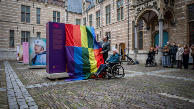 Bewoner John opent samen met de wethouder de expositie Oud Roze op de binnenplaats van Het Markiezenhof in Bergen op Zoom