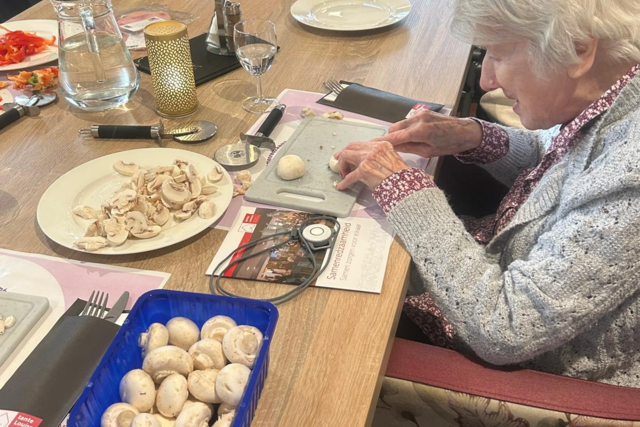 Een bewoner snijdt champignons voor de pizza bij de aftrap van het project